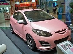 a pink car is on display in a showroom