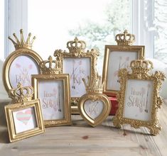 there are many gold frames with hearts and crowns on the windowsill, along with two red vases