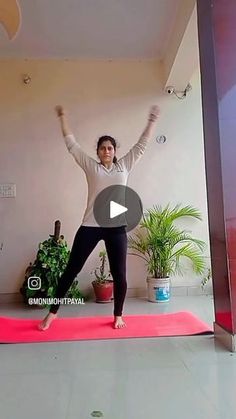 a woman standing on a yoga mat with her arms in the air