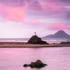 a person standing on top of a rock near the ocean