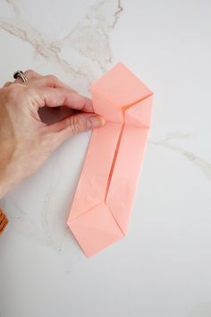 someone is cutting out an origami tie on a white counter top with scissors