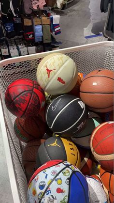 a basket filled with lots of different types of basketballs on display in a store