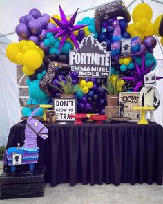 a table topped with balloons and decorations for a fortnite themed birthday party or celebration