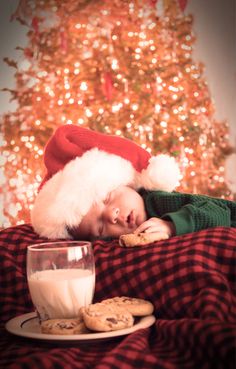 a person laying on top of a bed next to a plate of cookies and milk