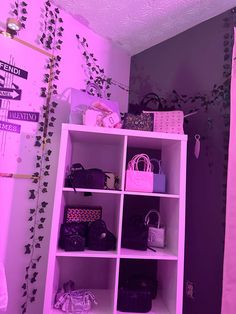 the closet is filled with handbags and purses in purple hued lighting on the walls