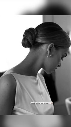 black and white photograph of a woman with her hair in a high bun, looking down