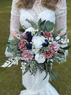 a bridal holding a bouquet of flowers in her hands and wearing a wedding dress