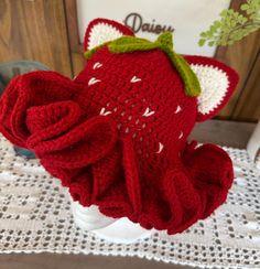 a crocheted hat with a green bow on it sitting on top of a table