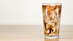 a glass filled with liquid sitting on top of a wooden table