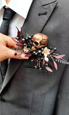 a person wearing a suit and tie holding a skull brooch