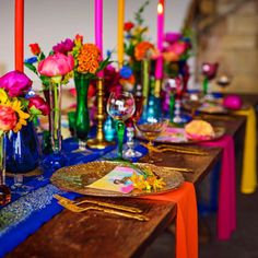 a long table is set with colorful flowers and candles for a festive dinner party