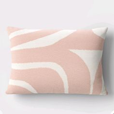 a pink and white pillow with wavy lines on the front, sitting against a wall