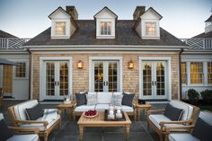 an outdoor living area with couches, chairs and tables in front of a house