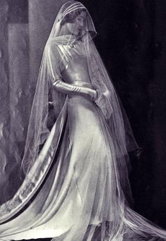 an old photo of a woman in a wedding dress with a veil on her head