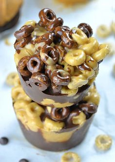 two chocolate cups filled with cereal and pretzels on top of eachother