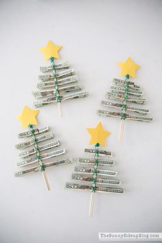 three christmas trees made out of dollar bills with green and yellow stars on them, sitting next to each other