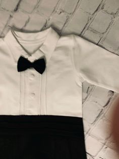 Little Baby Gentleman Bow-Tie One-Piece Black Suit:Introducing the Little Gentleman’s Bow-Tie One-Piece Black Tuxedo - a perfect blend of comfort and style for your little one's formal events. Created with the softest threads, it ensures maximum comfort while upholding the highest standards of elegance. This black tuxedo features an attached bow-tie, offering the look of luxury without sacrificing comfort. The one-piece design makes it easy to dress your baby, creating a hassle-free experience. Tuxedo Style Satin Bow For Black-tie Events, Elegant Tuxedo With Bow For Black-tie Events, Tuxedo Satin Bow For Black-tie Events, Tuxedo Bow For Black-tie Events, Baby Tuxedo Shirt, Baby Tuxedo, Fancy Dress Up, Black Bow Tie, Halloween Fancy Dress