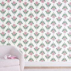 a white chair sitting in front of a wall with pink flowers on it's side