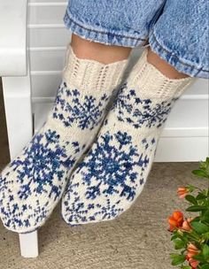 the legs of a woman wearing blue and white knitted socks with snowflakes on them