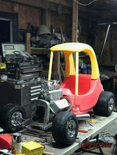 a red and yellow toy car sitting on top of a workbench in a garage