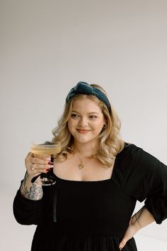 a woman in a black dress holding a drink