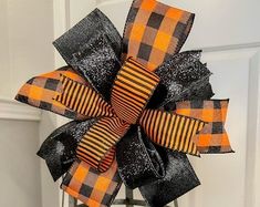 an orange and black plaid bow hanging from a metal stand in front of a door