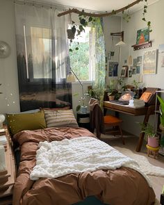 a bedroom with a bed, desk and hanging plants