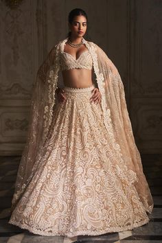 Beige lehenga featuring thread, pearl and crystal embroidery in paisley pattern and attached cancan. Paired with a padded blouse with cutwork embroidery at the waist, graded pearl details at the shoulder, and graded pearl strings in the back, along with an all over embroidered dupatta.
Components: 3
Pattern: Embroidered
Type Of Work: Pearl, Thread, Crystal
Neckline: Plunging V
Sleeve Type: Sleeveless
Fabric: Organza
Color: Beige
Other Details: 
Attached cancan
Padded blouse
Lehenga length: 45 - Pearl Strings, Cut Work Embroidery, Seema Gujral, All Over Embroidery, Crystal Embroidery, Pearl Details, Indian Dresses Traditional, Indian Bridal Outfits, Indian Wedding Outfits