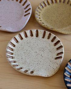 four plates sitting on top of a wooden table next to each other with different designs