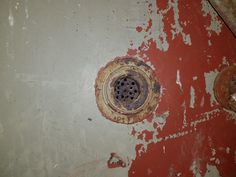 an old rusted metal drain on the side of a red and white painted wall