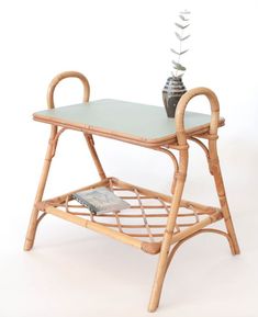 a bamboo table with a magazine rack and vase on the top, against a white background