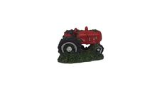 a small red tractor sitting on top of a lush green field