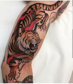 a tiger tattoo on the leg of a man with red ribbon around his neck and foot