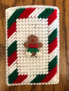 a knitted christmas decoration with a gingerbread man on the front and green, red, and white stripes