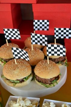 hamburgers with black and white checkered flags on them are served in small trays