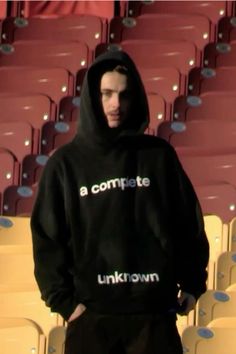 a man wearing a black hoodie standing in front of rows of chairs