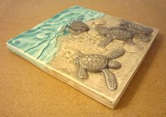 two sea turtles swimming in the ocean on a ceramic tile wall art piece that is handmade and ready to be displayed