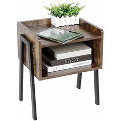 a small wooden table with two books and a plant on the top, sitting next to each other