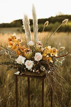 a vase filled with flowers sitting on top of a metal stand in the middle of a field