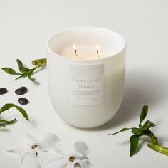 a white candle sitting on top of a table next to flowers