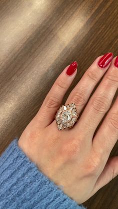 a woman's hand with red nails and a ring on it