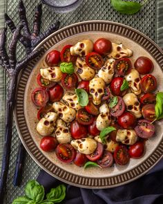 a plate filled with tomatoes and skulls on top of a table next to silverware