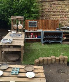 a wooden table sitting in the middle of a yard next to a brick wall and green grass