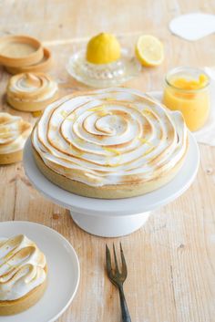 there is a cake on the table with lemons and other dessert items around it