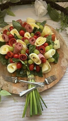 a wooden plate topped with lots of flowers on top of a table next to utensils