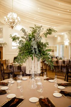 a table set with place settings, plates and flowers in a vase on top of the table