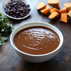 a white bowl filled with brown sauce next to other ingredients on a wooden table top