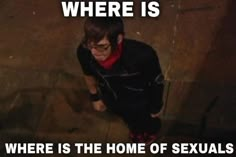 a man sitting on the ground in front of a wall with text that reads, where is there is the home of sexuals?