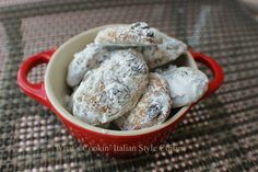 a red bowl filled with powdered sugar covered cookies