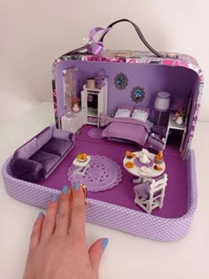 a woman's hand is touching the inside of a doll house with furniture and accessories